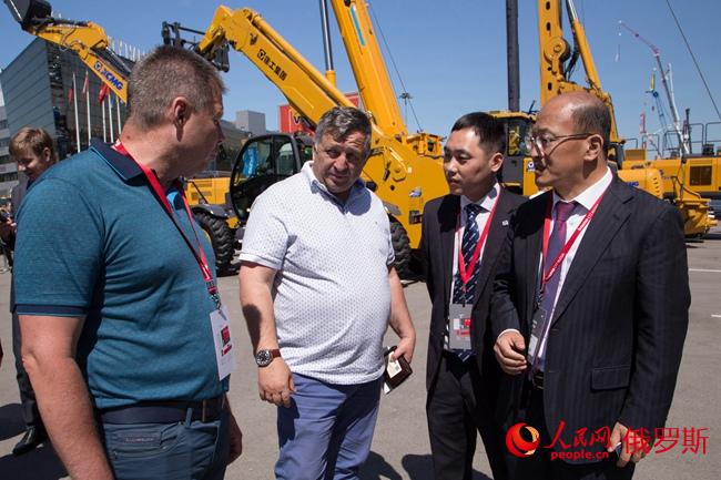 徐工機器副總裁、徐工團體收支口公司總司理劉建森向俄經(jīng)銷商先容設備（右一）（實習生 陳效坤 攝）